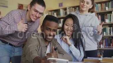 一群<strong>国际</strong>学生在大学图书馆的智能<strong>手机</strong>摄像头上开心地微笑和自拍